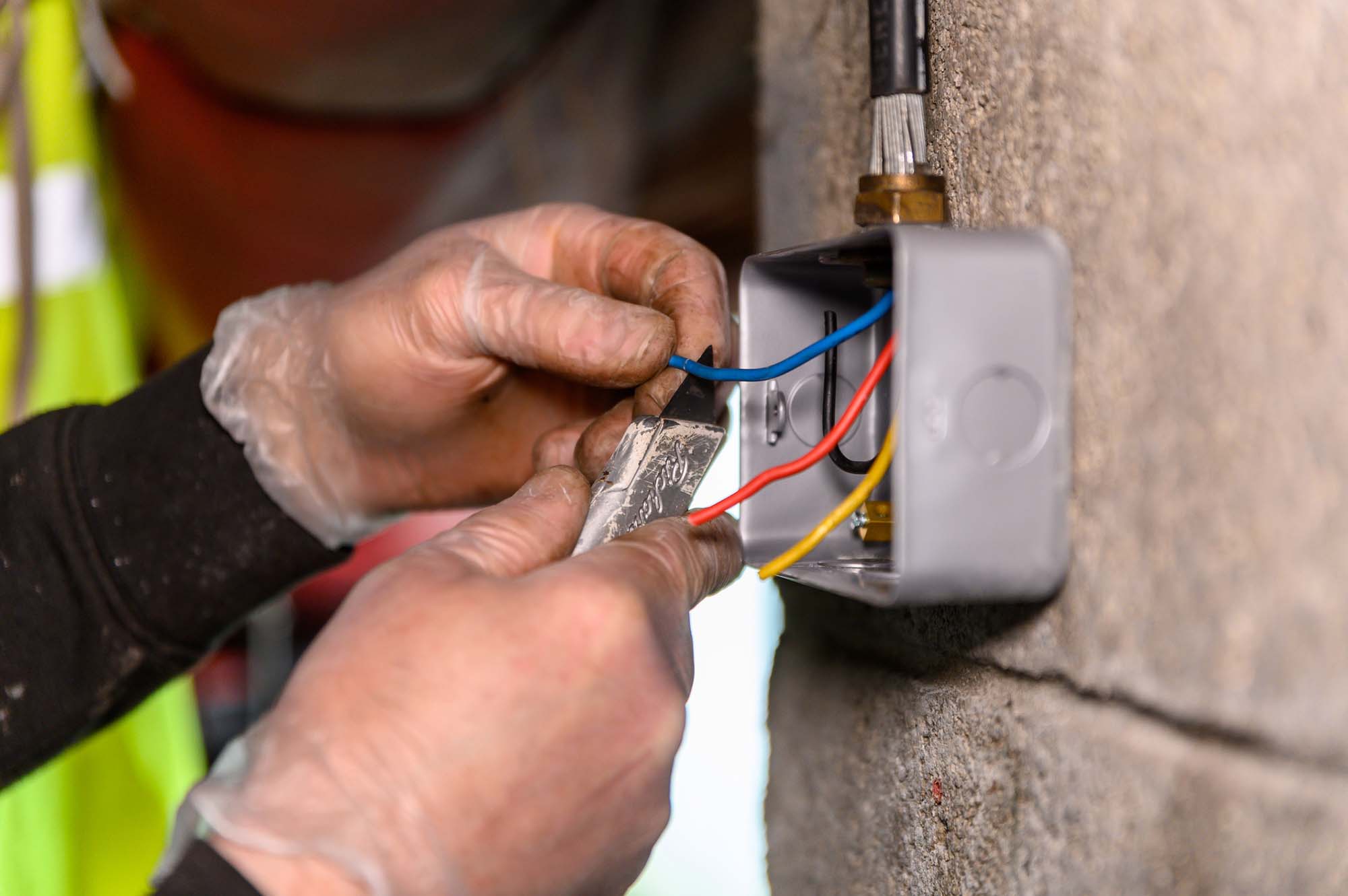 Male electrician cutting wire for socket plug on garage wall, uk socket
